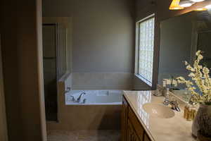 Bathroom with vanity, a stall shower, a garden tub, and tile patterned floors