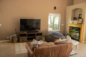 Carpeted living area with baseboards and a towering ceiling