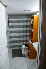 Full bath featuring a textured ceiling, tile patterned flooring, curtained shower, and vanity