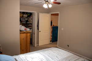 Bedroom with a textured ceiling, a closet, carpet floors, and a ceiling fan