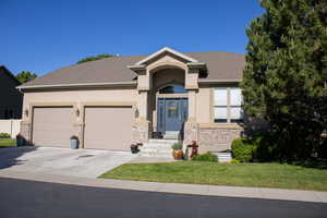 Ranch-style home with concrete driveway, a garage, stucco siding, a front lawn, and stone siding