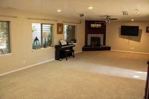 Carpeted living area with ceiling fan, a fireplace with raised hearth, and recessed lighting