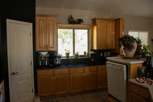 Kitchen with white dishwasher, light tile patterned floors, and decorative backsplash