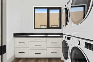 Laundry room featuring estacked washer and dryer, cabinet space, and dark wood-style flooring