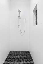 Full bathroom featuring tiled shower and brick patterned flooring