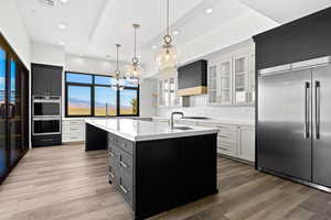 Kitchen featuring appliances with stainless steel finishes, an island with sink, recessed lighting, backsplash, and light wood-style flooring