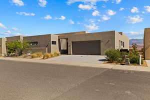 Pueblo revival-style home with an attached garage, driveway, stucco siding, and a mountain view