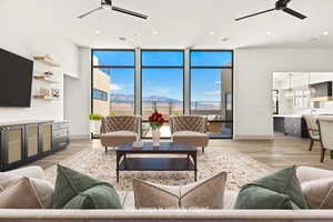 Living area with ceiling fan, light wood finished floors, a wall of windows, and recessed lighting