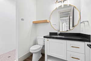 Bathroom featuring vanity, a tile shower, and wood finished floors