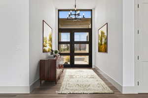 Entrance foyer with a chandelier, wood finished floors, healthy amount of natural light, and a high ceiling