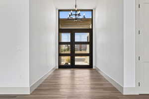 Foyer featuring a chandelier, wood finished floors, plenty of natural light, and a wall of windows