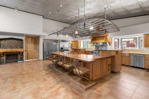 Kitchen featuring stainless steel appliances, a large island, a kitchen breakfast bar, a fireplace, and light countertops