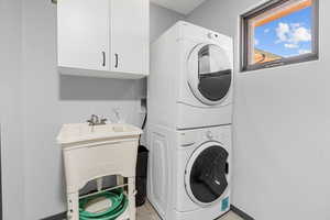 Laundry area with stacked washer / drying machine and cabinet space