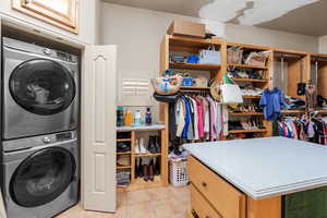 Washroom featuring stacked washer / drying machine and light tile patterned flooring