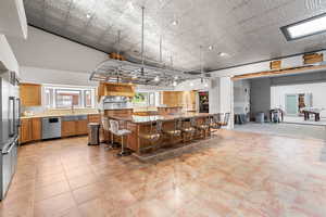 Kitchen featuring stainless steel appliances, a breakfast bar area, light countertops, a large island, and an ornate ceiling