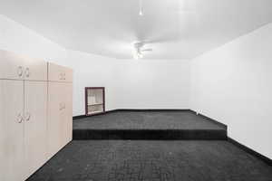 Unfurnished bedroom featuring dark colored carpet and a ceiling fan