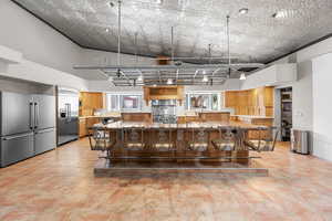 Kitchen featuring high quality fridge, built in fridge, plenty of natural light, a breakfast bar, and a high ceiling