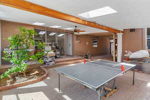 Game room featuring a skylight, brick patterned floors, beam ceiling, and a ceiling fan
