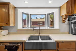 Kitchen featuring light countertops, brown cabinetry, recessed lighting, and dishwashing machine