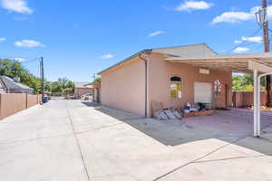 View of side of home featuring driveway, an attached carport, and stucco siding