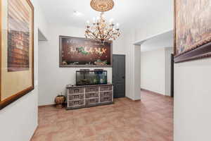 Corridor featuring a chandelier and baseboards