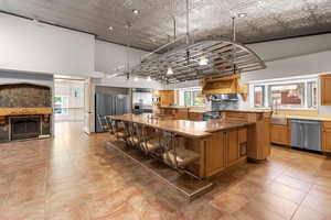 Kitchen featuring stainless steel appliances, a large island, a breakfast bar, a high ceiling, and light countertops