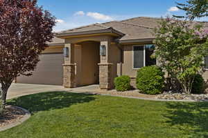 View of front of house featuring stucco siding, an attached garage, a front yard, a tiled roof, and driveway