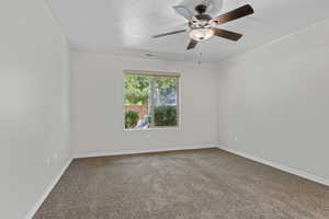 Carpeted spare room with ceiling fan and baseboards