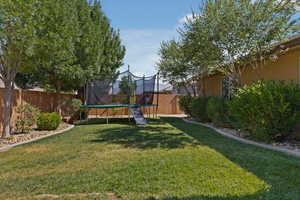 Fenced backyard featuring a trampoline