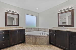 Bathroom featuring two vanities and a garden tub