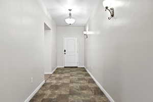 Doorway to outside with stone finish floors and baseboards