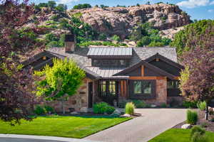 View of front of property featuring a standing seam roof, stone siding, a front yard, and a chimney