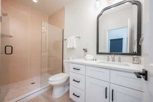 Bathroom featuring a stall shower, vanity, and wood finished floors