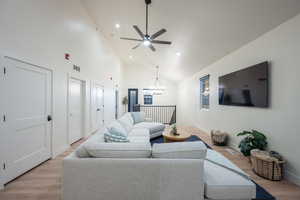 Living area featuring light wood-style floors, a ceiling fan, high vaulted ceiling, a chandelier, and recessed lighting