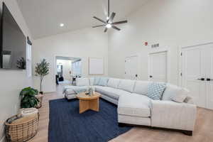 Living room featuring high vaulted ceiling, ceiling fan, light wood finished floors, and recessed lighting