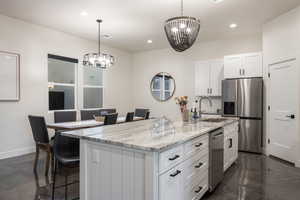 Kitchen featuring appliances with stainless steel finishes, a chandelier, finished concrete flooring, a kitchen bar, and recessed lighting
