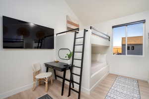 Bedroom with wood finished floors and high vaulted ceiling