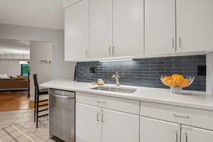 Kitchen with stainless steel dishwasher, light countertops, and white cabinets