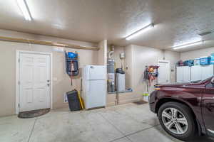 Garage featuring freestanding refrigerator and water heater