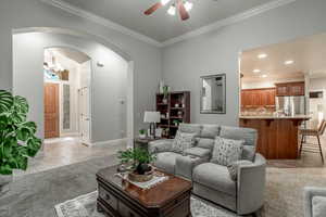 Living area with ceiling fan, ornamental molding, arched walkways, a chandelier, and recessed lighting