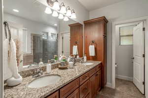 Primary bathroom with a shower stall, double vanity, and recessed lighting