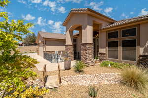 View of side of property with stucco siding, a tiled roof, and stone siding