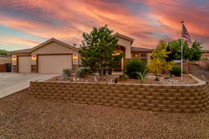 View of front of property with concrete driveway, stucco siding, a tiled roof, an attached garage, and stone siding