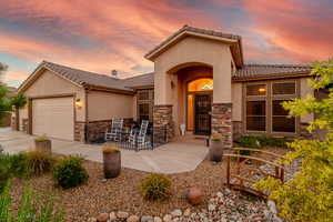 Mediterranean / spanish-style house with stone siding, a tiled roof, an attached garage, and stucco siding