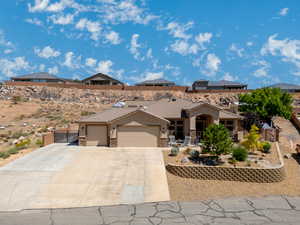 View of front facade featuring stucco siding, an attached garage, a tile roof, driveway, and stone siding