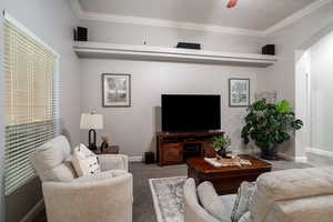 Living area featuring carpet, ornamental molding, arched walkways, and ceiling fan