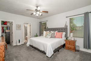 Primary bedroom featuring a walk in closet, carpet flooring, a closet, a ceiling fan, and ensuite bathroom