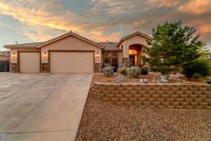 View of front facade with stone siding, stucco siding, an attached garage, driveway, and a tile roof