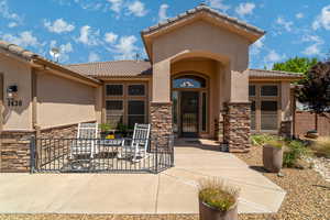 Entrance to property featuring stone siding, a tile roof, and stucco siding