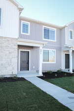 View of front of house featuring a front yard, stone siding, and board and batten siding